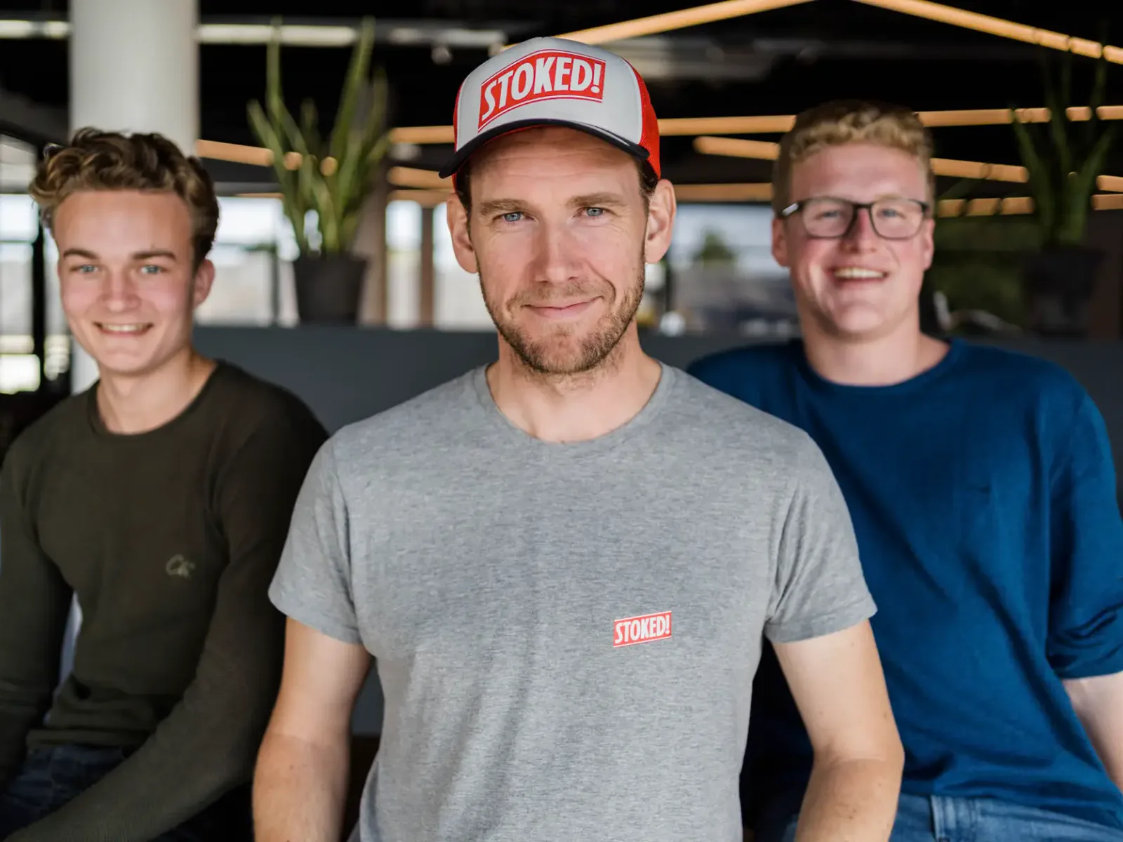 Drie glimlachende medewerkers van het Nederlandse supportteam in een modern kantoor